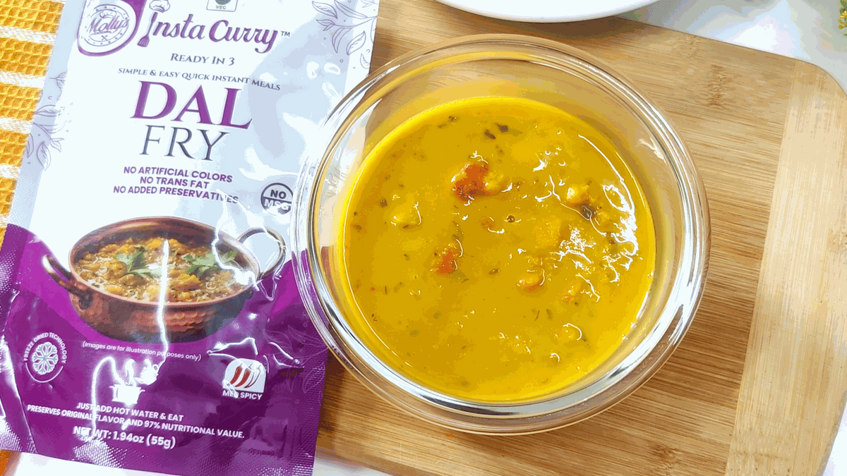 Dal Fry 2-Pack featuring a purple and white instant curry pouch beside golden lentil curry in a glass bowl