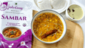 Molly's Insta Curry® Sambar instant meal packet beside golden lentil stew with vegetables and a cinnamon stick
