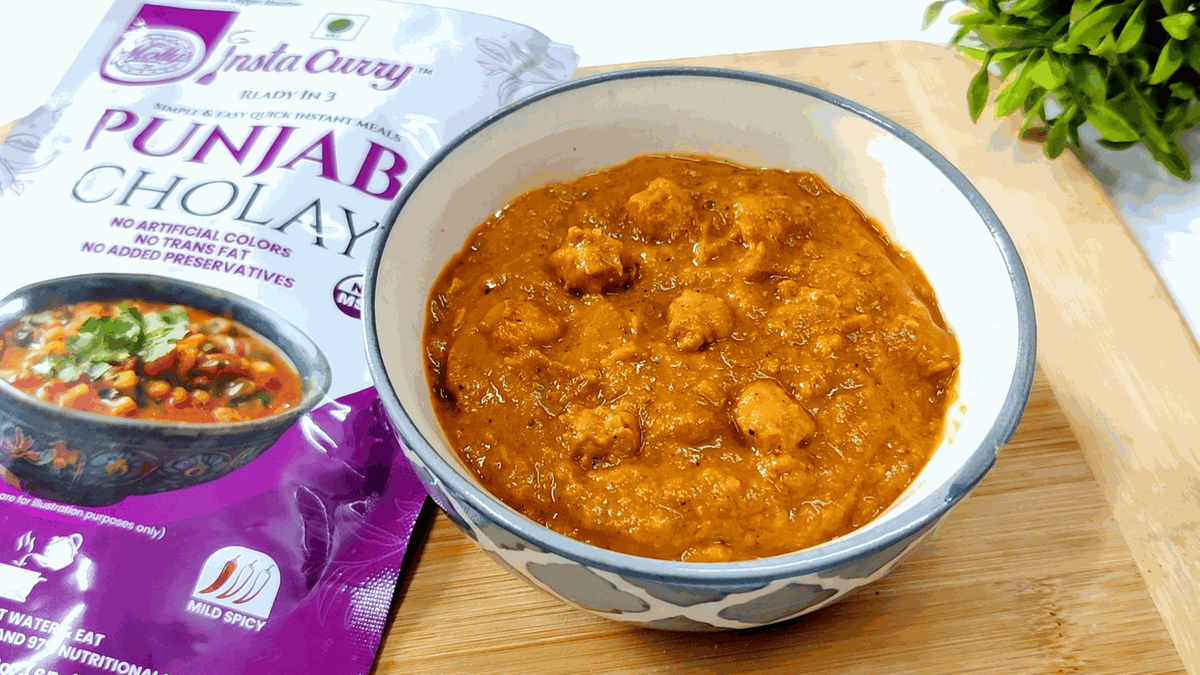 Punjabi Cholay chickpea curry with golden-brown sauce and visible chickpeas beside a purple Insta Curry pouch
