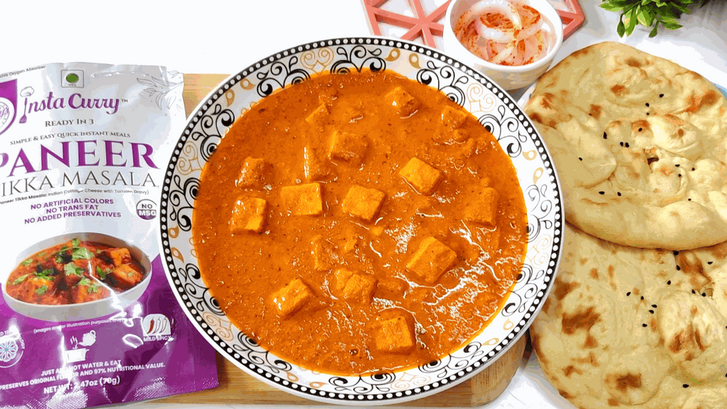 Paneer tikka masala in creamy orange curry with paneer cubes beside naan and a pouch; Tawa Pulao is not shown.